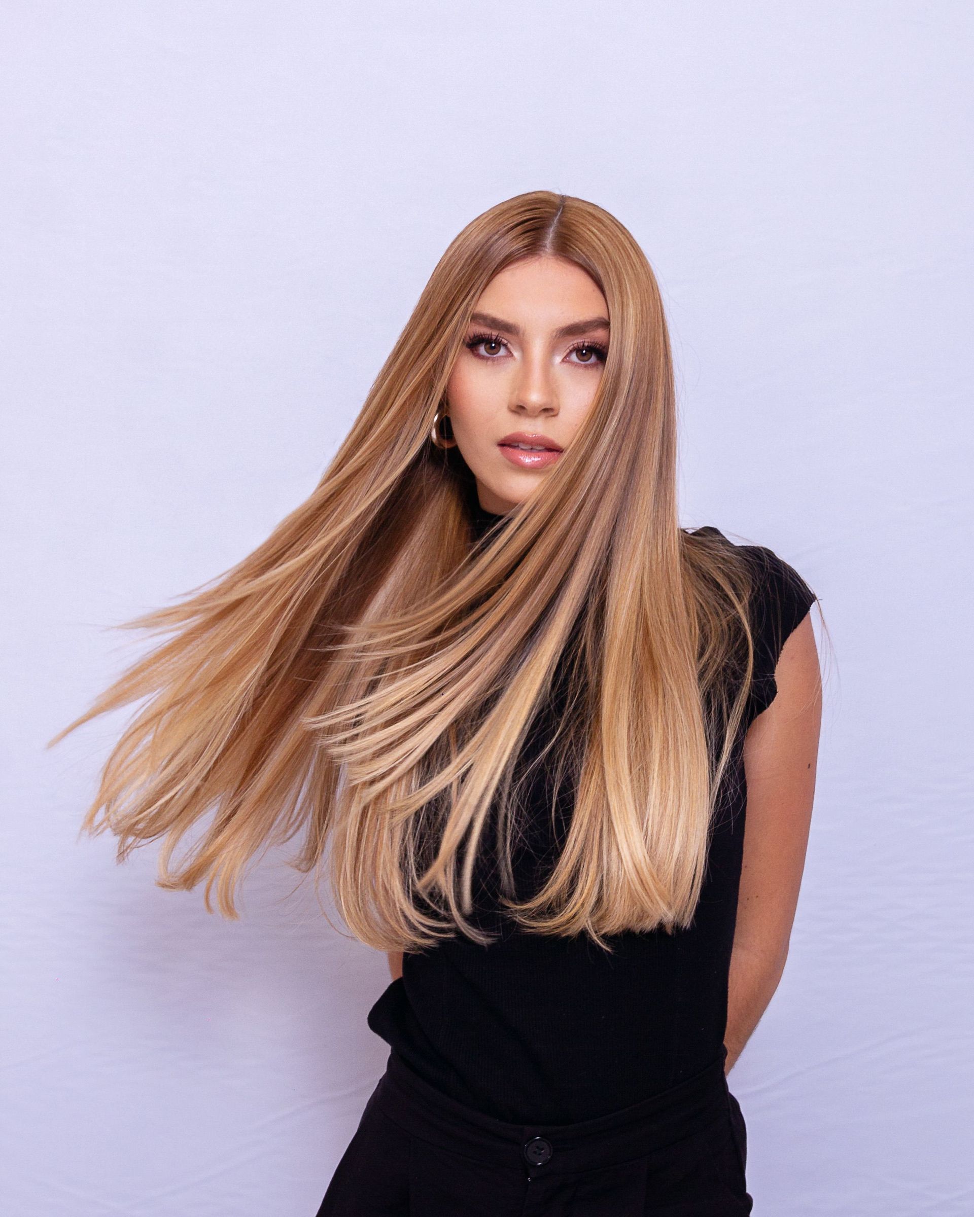 Stylish woman with long blonde hair in a studio, exuding elegance and modern fashion.